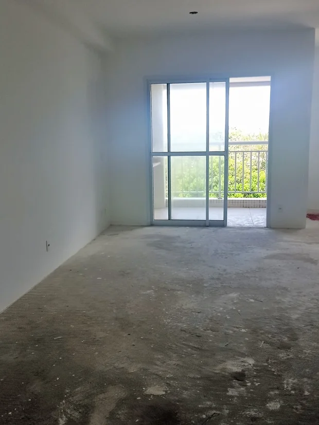 Apartamento vazio antes da reforma, com contrapiso à mostra e a varanda ao fundo.