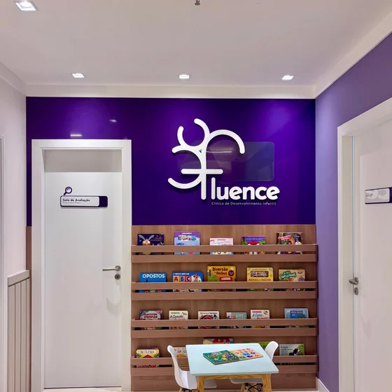 Espera da Clínica Fluence, com o letreiro branco sobre a parede roxa.