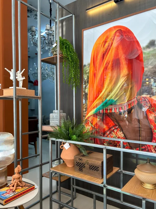 Painel laranja com obra de arte e objetos de coleção sobre a estante.