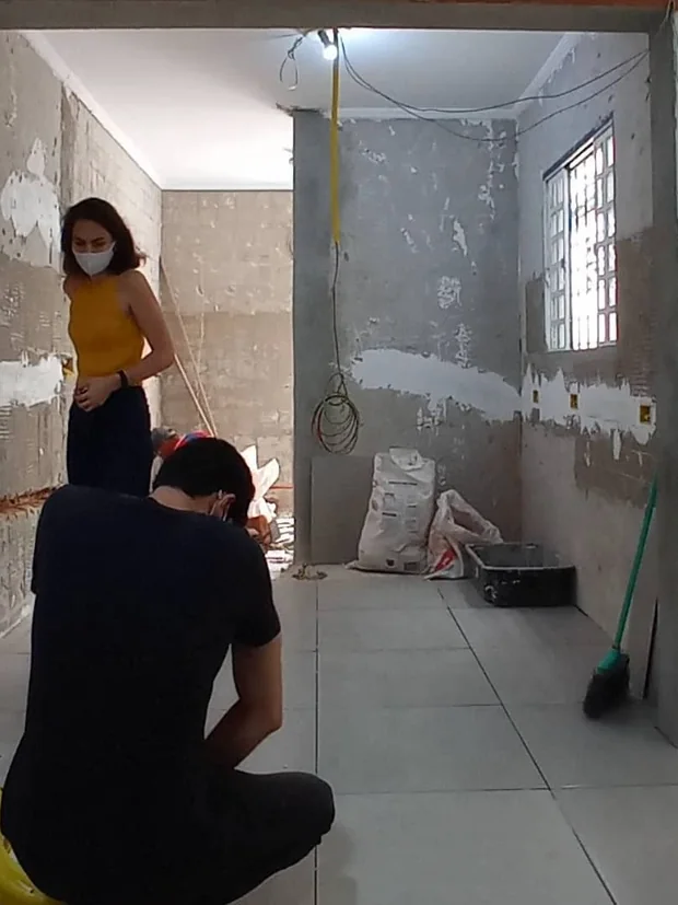 Equipe conferindo o espaço em obra, com paredes preparadas para acabamento.