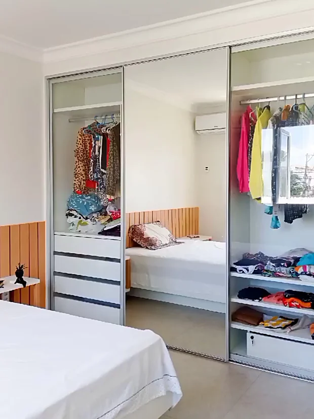 Suíte entregue, com closet de portas espelhadas ao lado da cama e a cabeceira ripada.