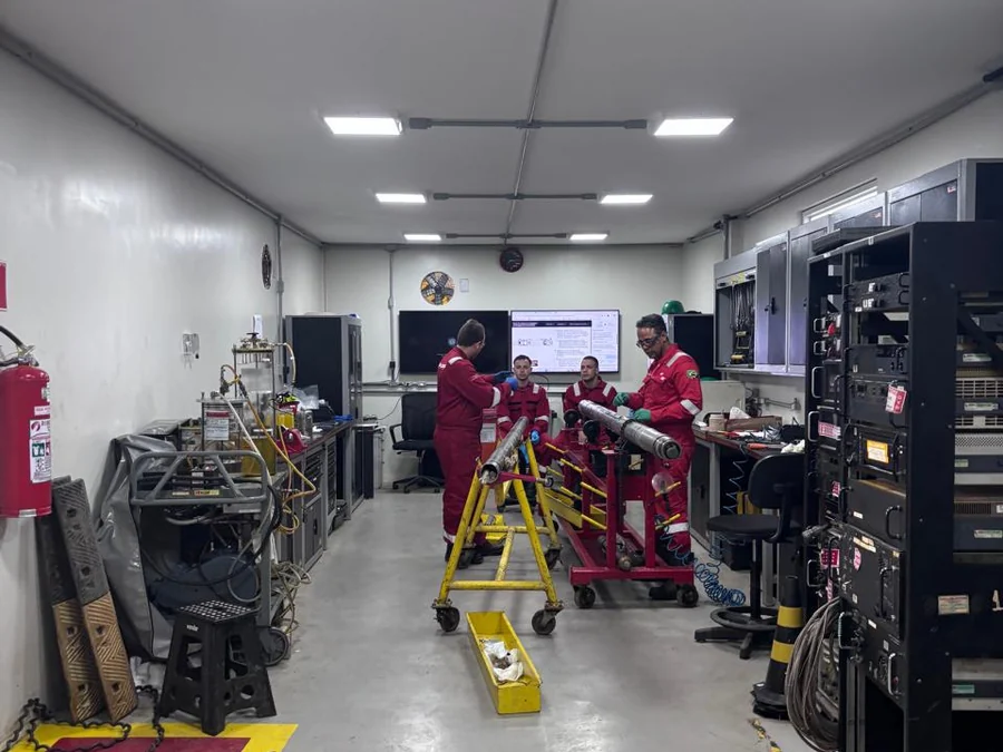 Equipe de uniforme vermelho trabalhando entre os racks de equipamento.